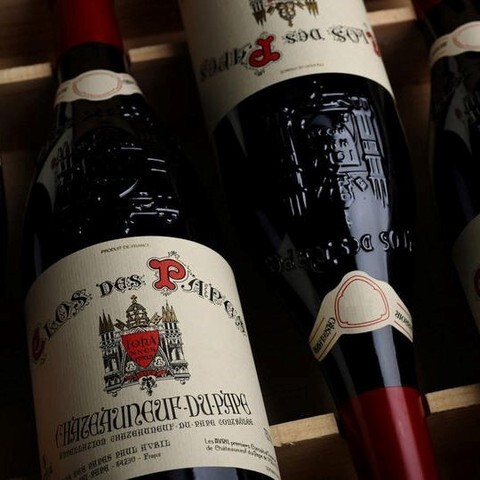 Clos des Papes Châteauneuf-du-Pape red wine bottles resting in a wooden crate.