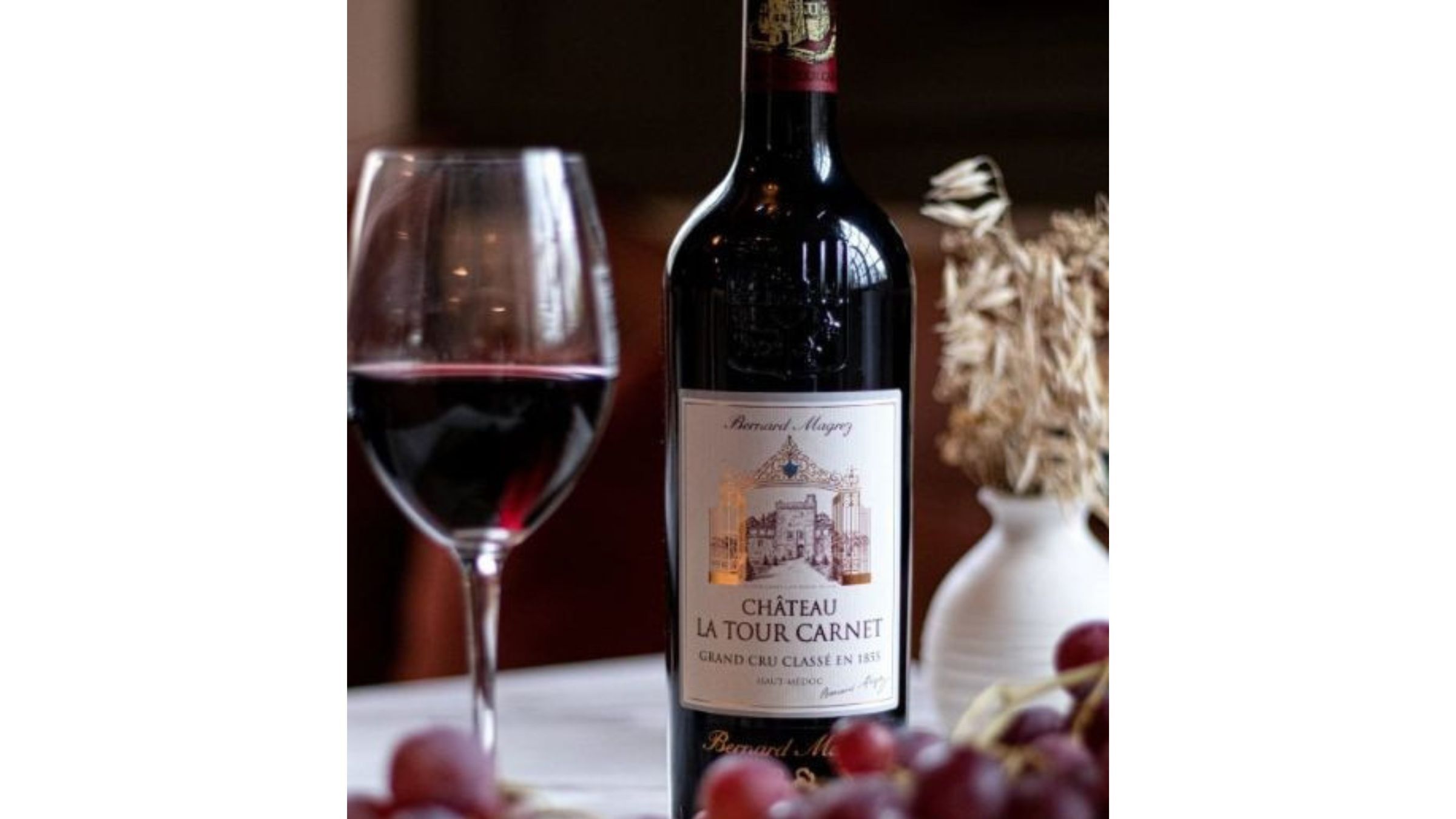 Red wine bottle from WHWC and glass on a softly lit table, highlighting classic structure and deep ruby color.