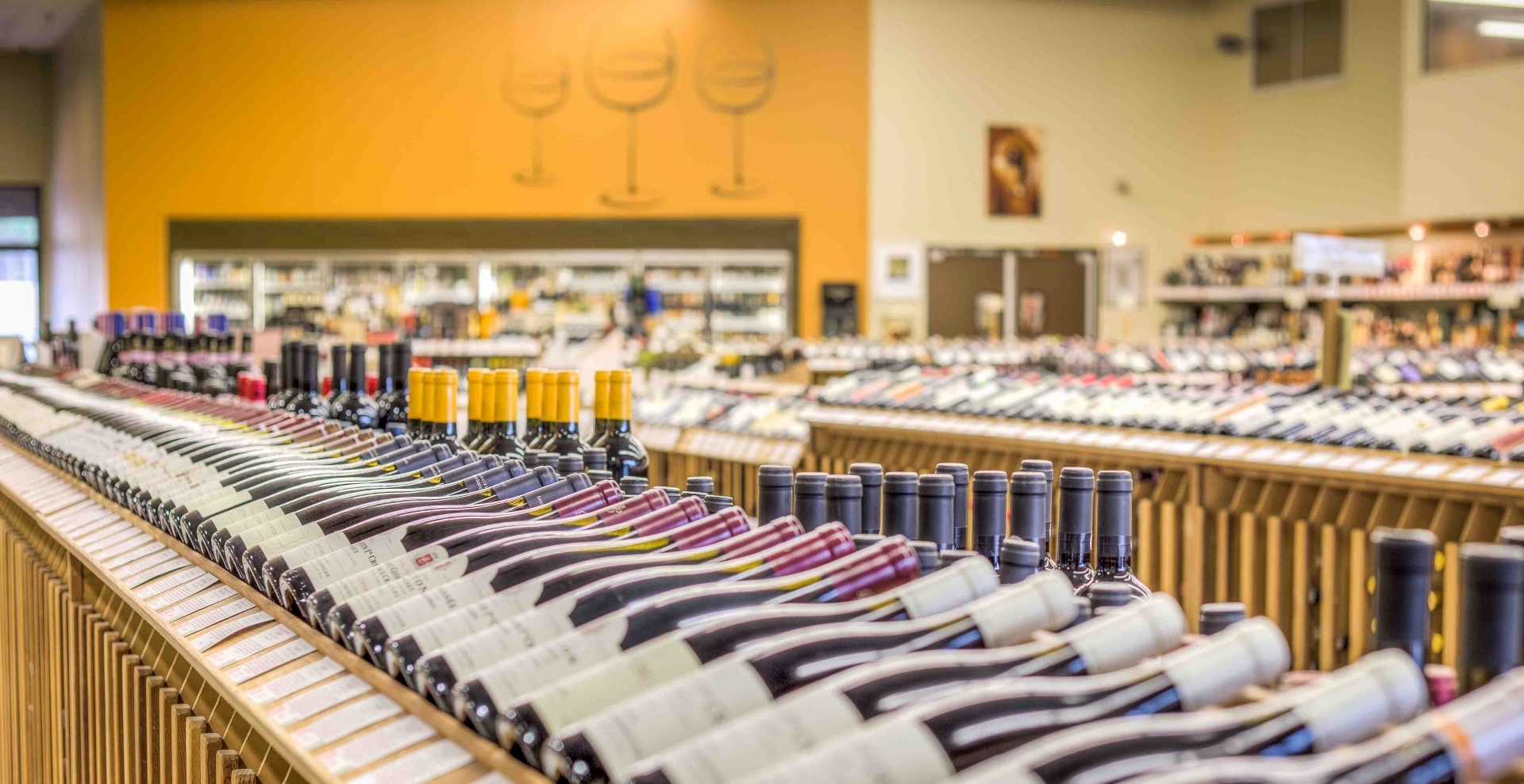 Rows of red wine bottles lying in angled wooden racks inside Woodland Hills Wine Company’s retail store.