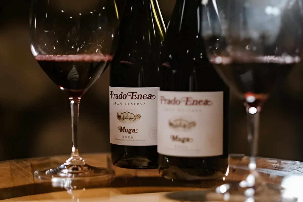 Two bottles of Prado Enea Gran Reserva Rioja Muga wine standing between two partially-filled glasses.