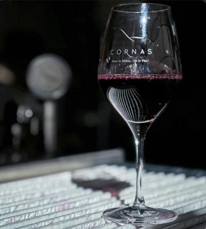 Wider bowl glass, handling red wine to offer an elegant experience, placed on a glass table.
